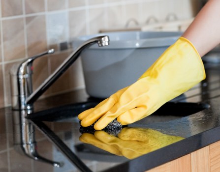 Professional cleaner dusting and vacuuming a modern living room